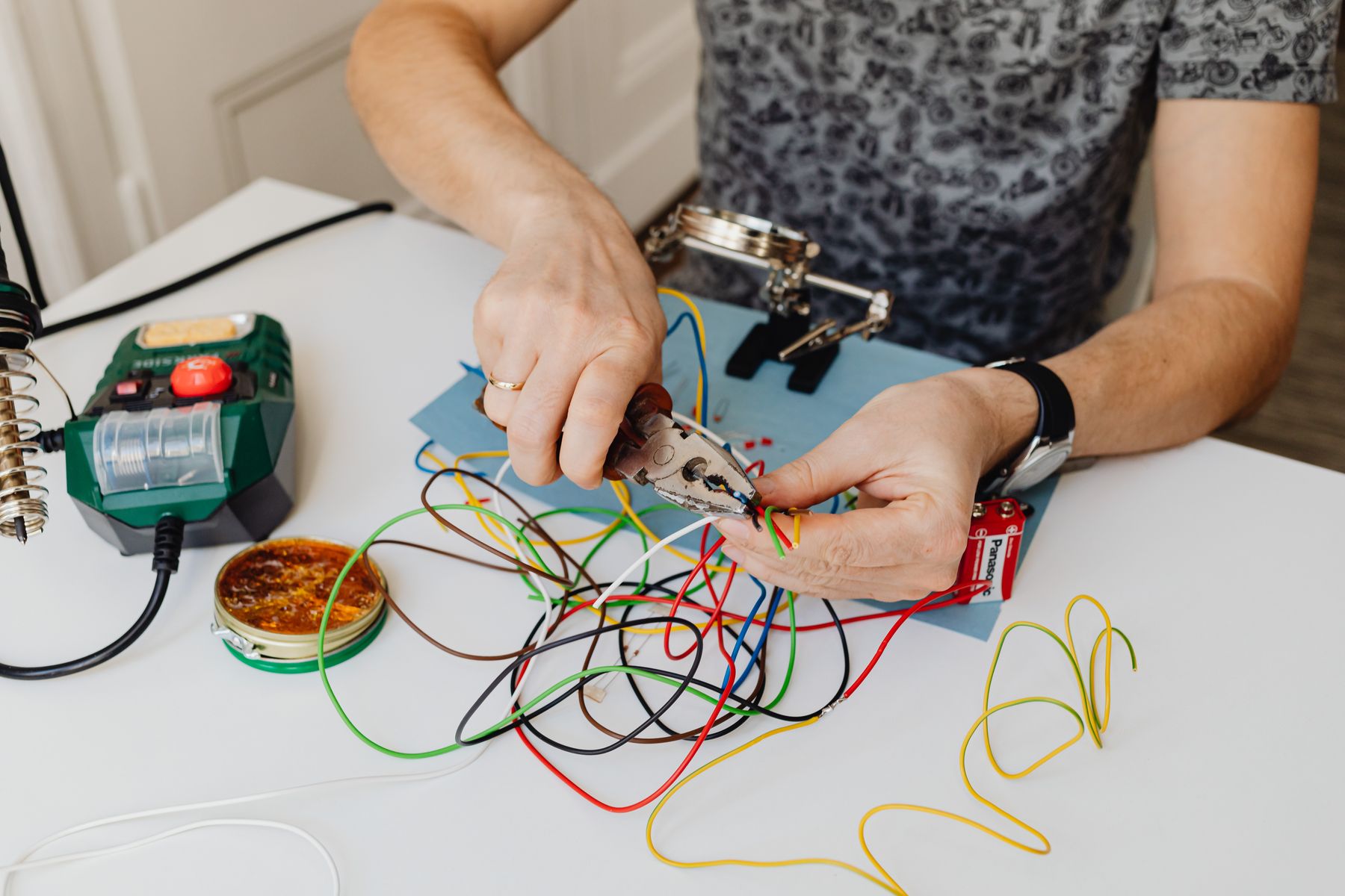 Technician cutting coloured electrical wires with pliers